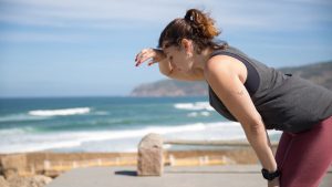 A woman rests after exercise, overlooking the ocean in Portugal's scenic seascape.